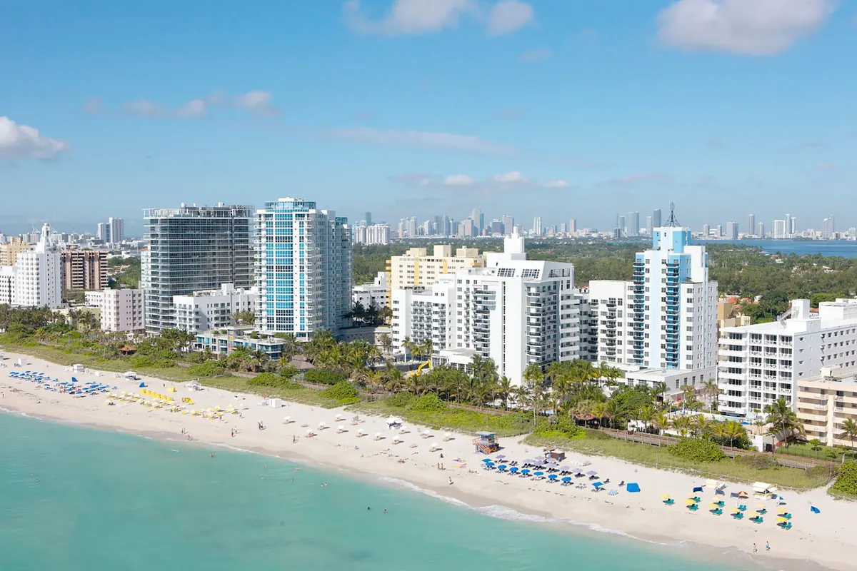 Aerial view of Miami Beach hotels and sand with the downtown Miami skyline in the distance